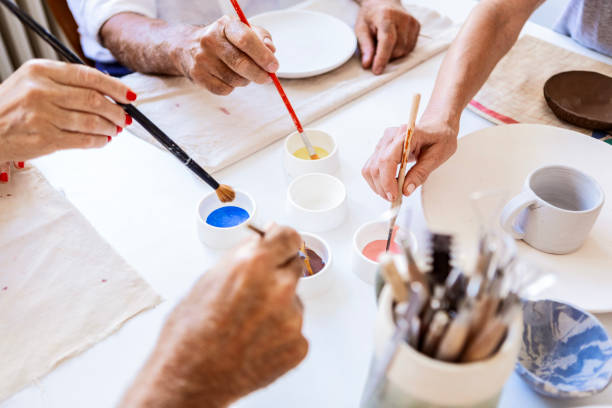 Table of residents engaged in painting ceramics together around a table